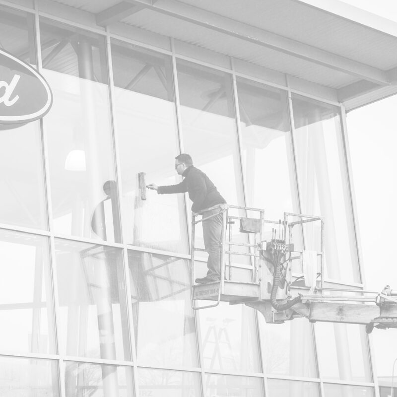 Person reinigt eine Glasfassade von einer Hebebühne aus.