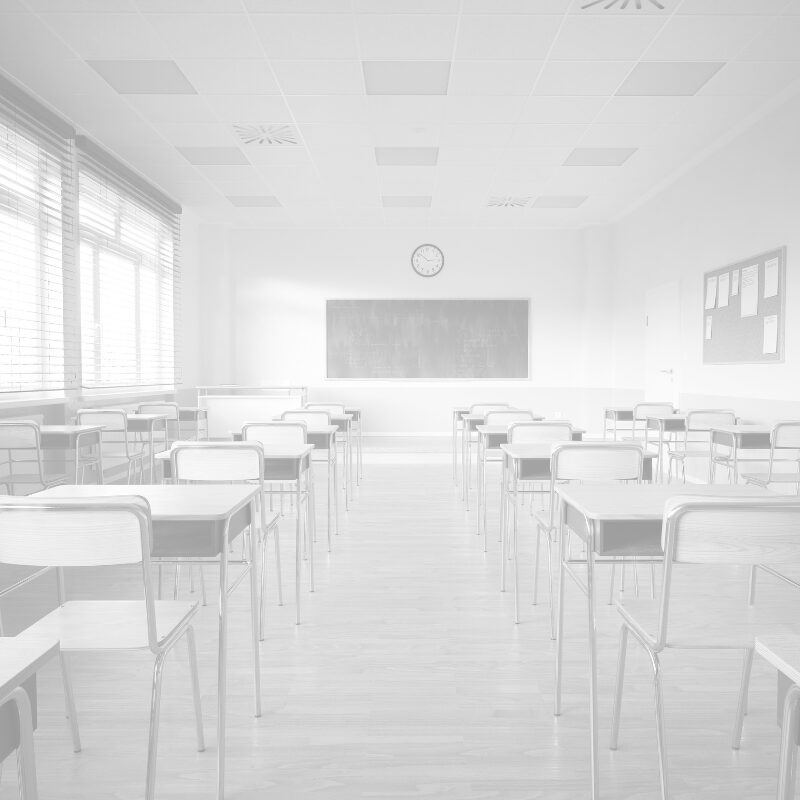 Leeres Klassenzimmer mit Tischen und Stühlen, hell und ordentlich.