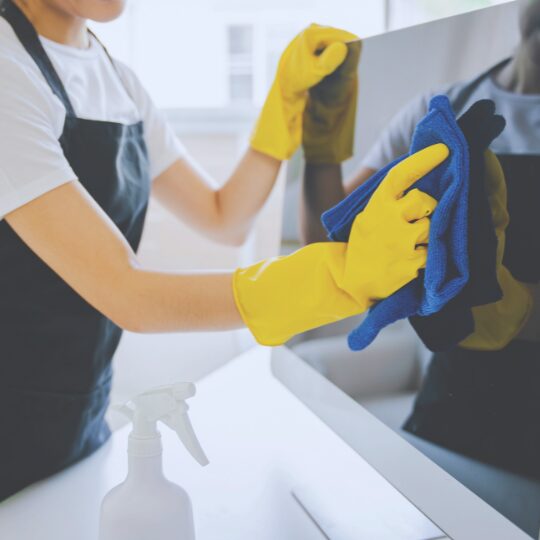 Objektreinigung im Buero – Tip-Top Reinigung Reinigungskraft wischt Monitor mit Mikrofasertuch und Handschuhen – hygienische Objektreinigung im Buero.