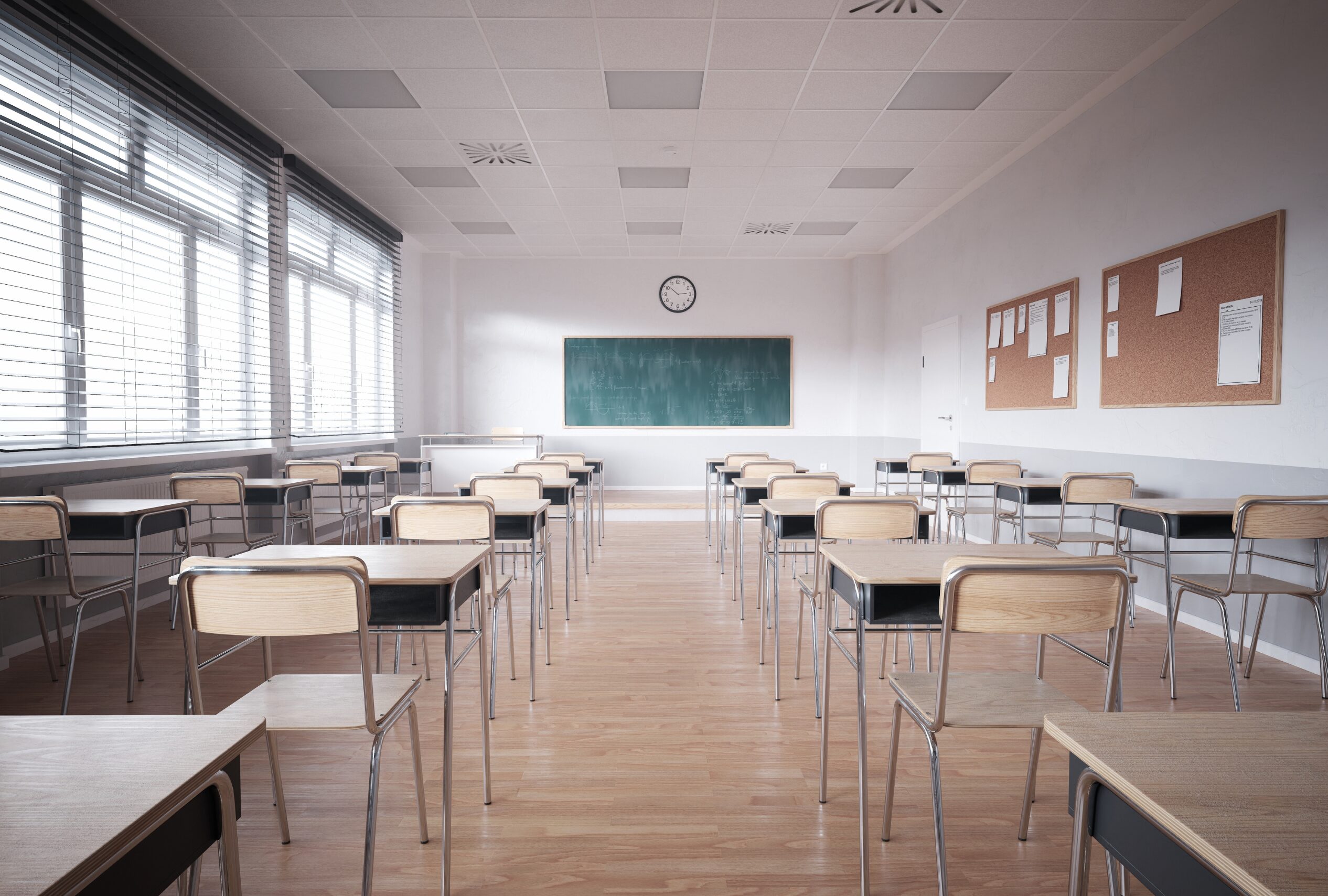 Leeres Klassenzimmer mit Tischen, Stuehlen und Tafel.